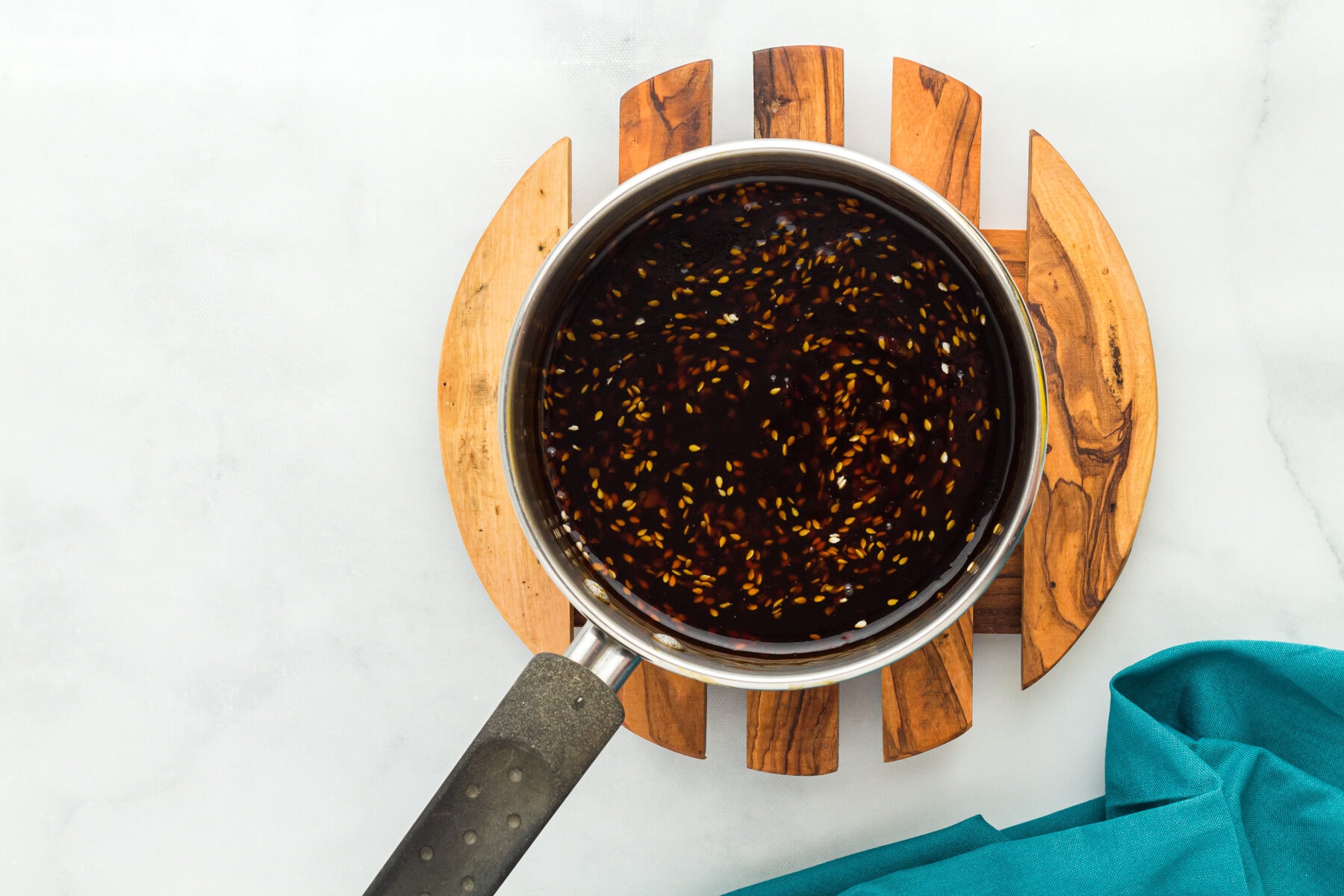 Overhead view of gluten free teriyaki sauce with sesame seeds in a saucepan.