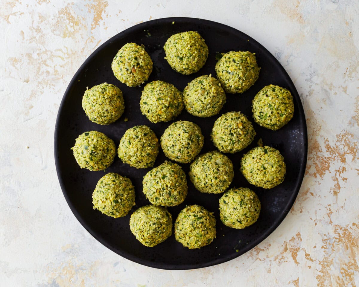 formed gluten-free falafel balls on a black plate.