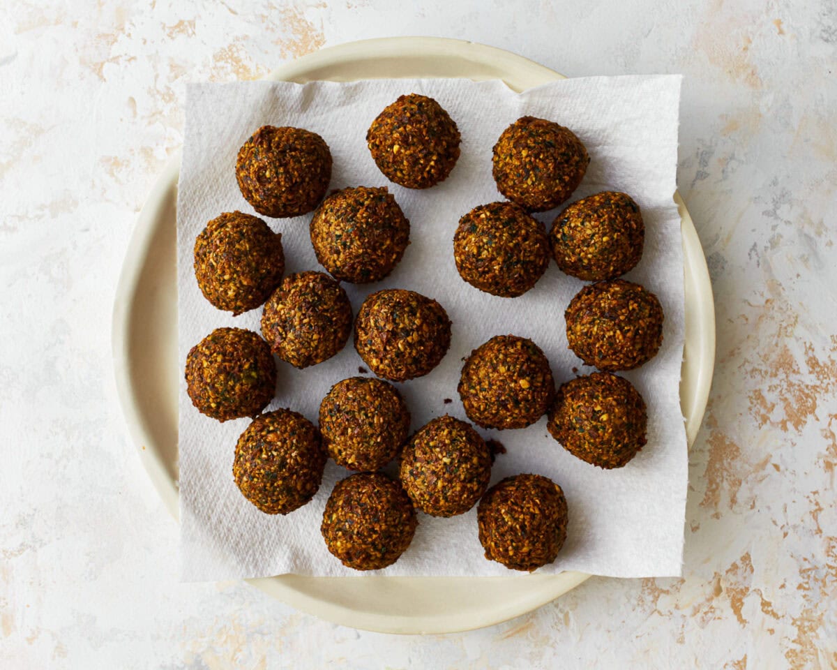 draining gluten-free falafel balls on paper towels on a white plate.