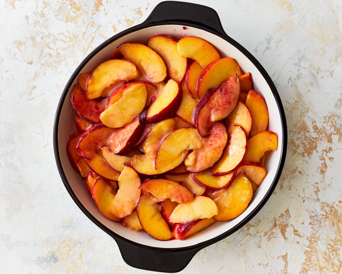 Sliced peaches in a baking dish.