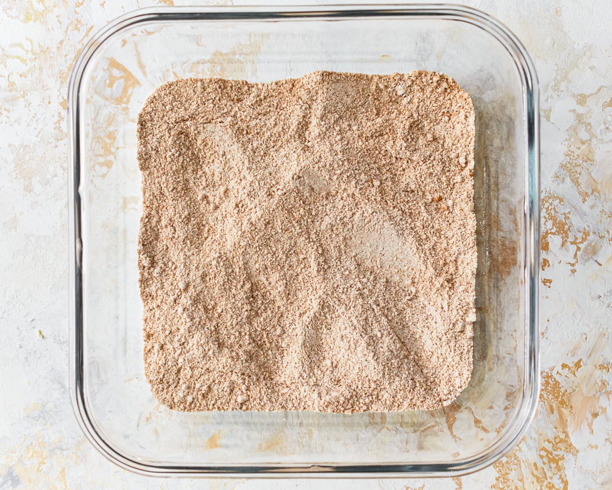 Sugar, flour, cinnamon, and salt in a glass baking dish for gluten-free peach crisp