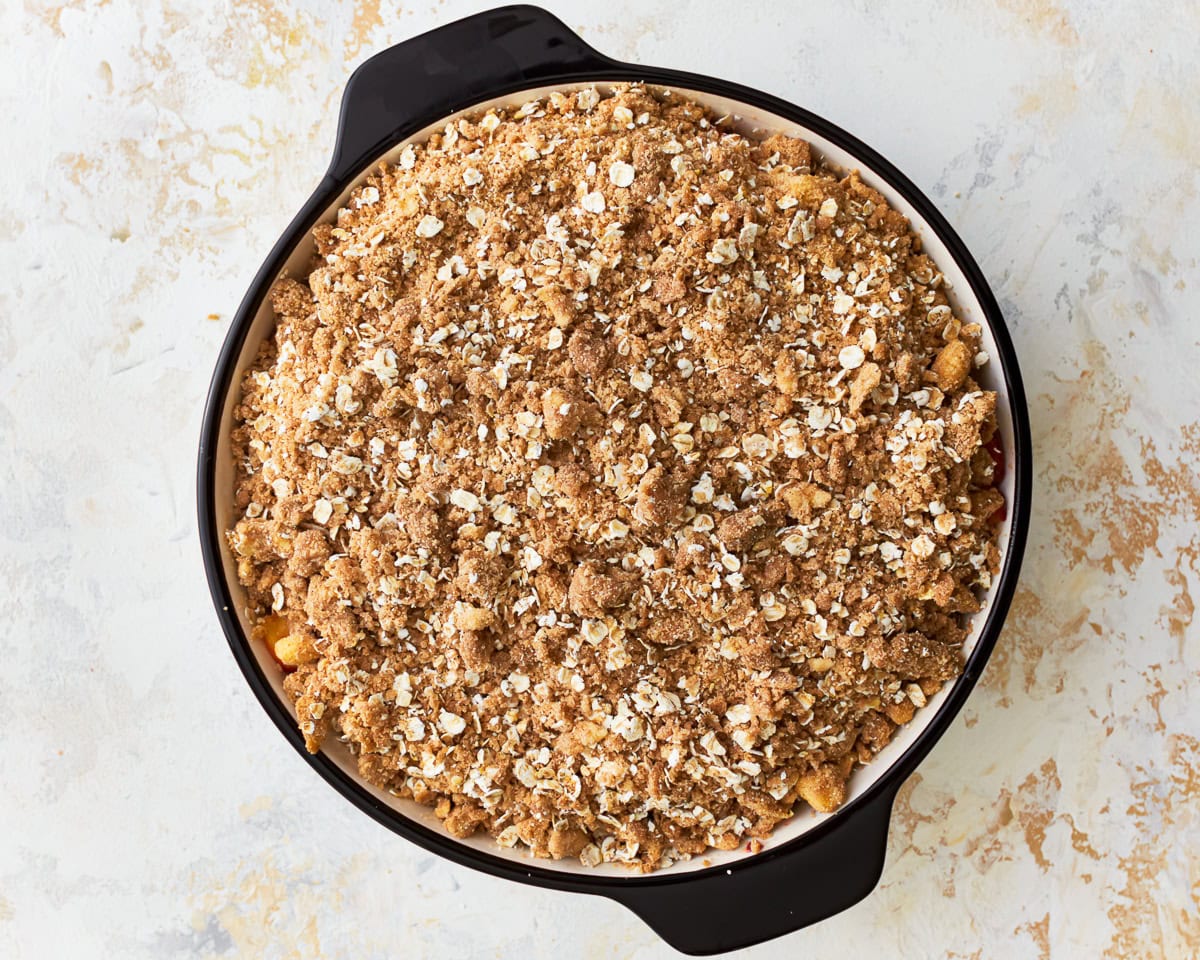 Gluten-free peach crisp in a baking dish ready to be baked