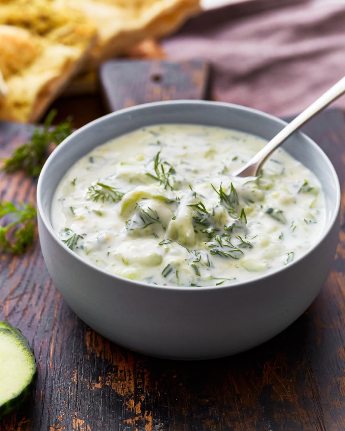 Side view of a bowl of dairy-free tzatziki topped with fresh dill.