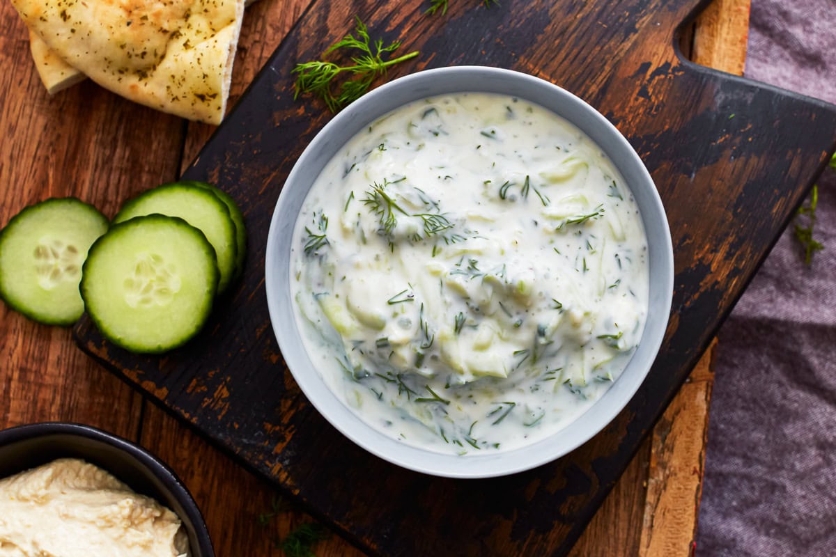 A bowl of dairy-free tzatziki on a wooden chopping board