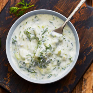 A close up of a fork taking some dairy-free tzatziki from a bowl.