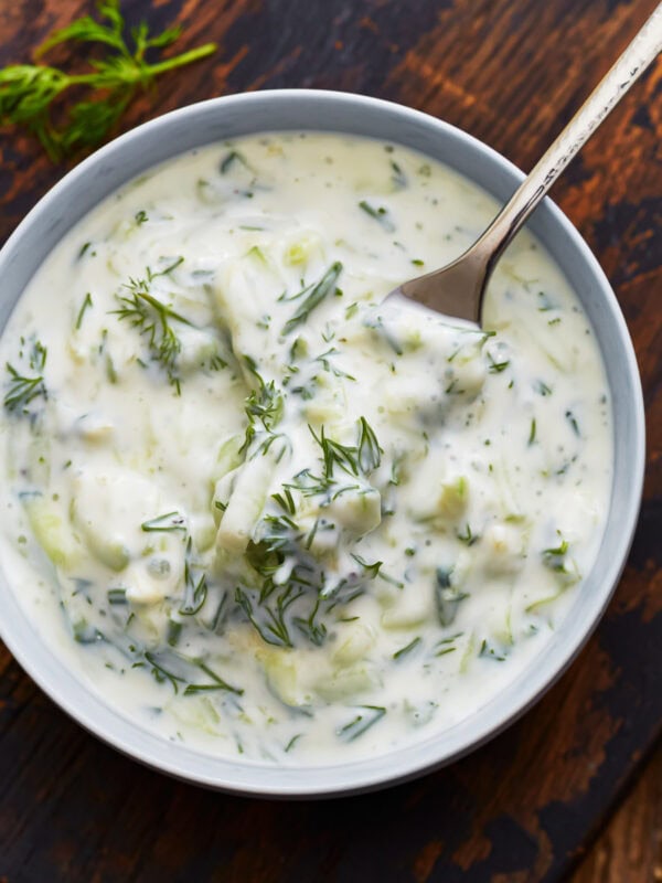 A close up of a fork taking some dairy-free tzatziki from a bowl.