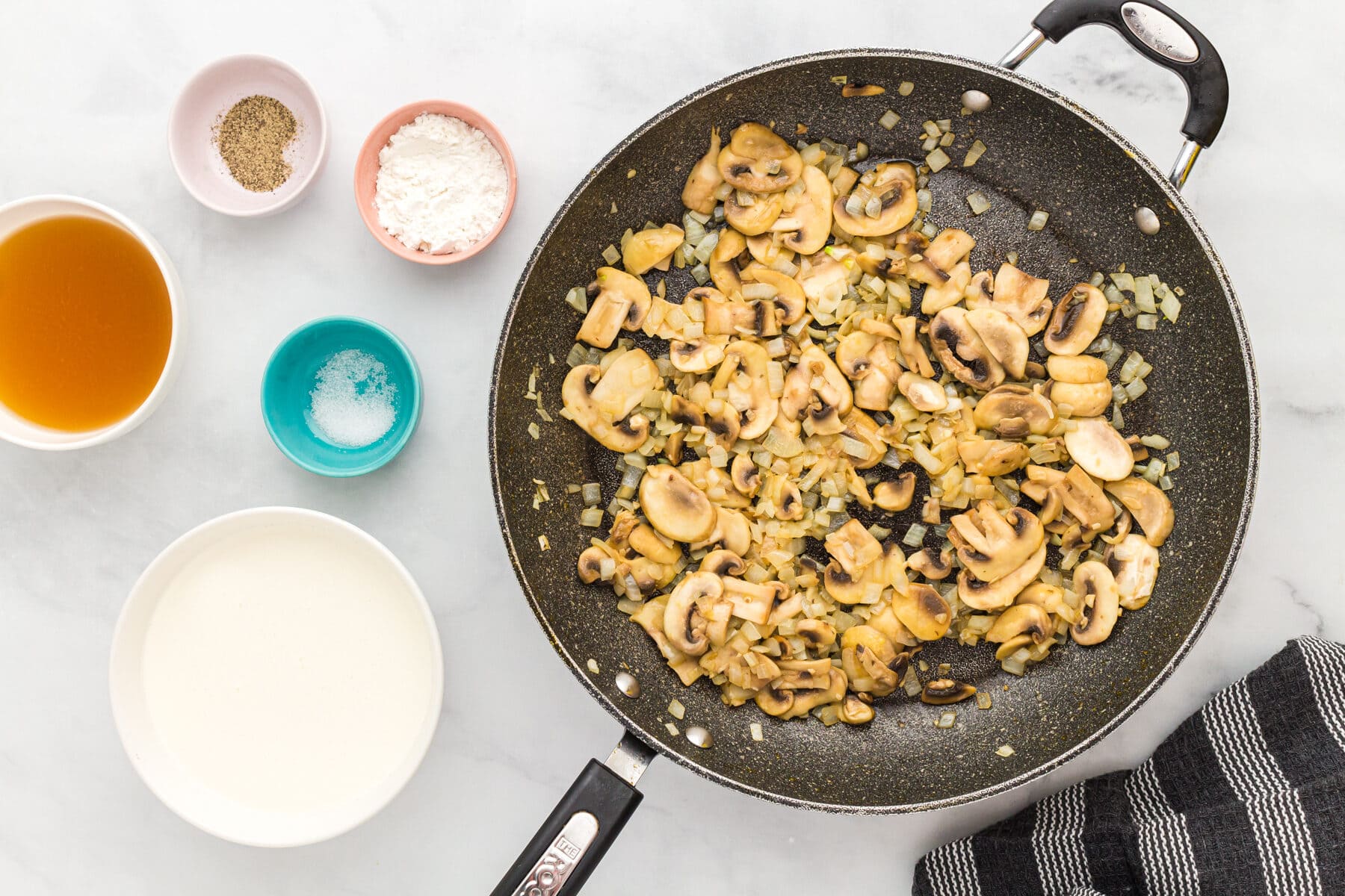 Sliced onions, mushrooms, and garlic in a skillet