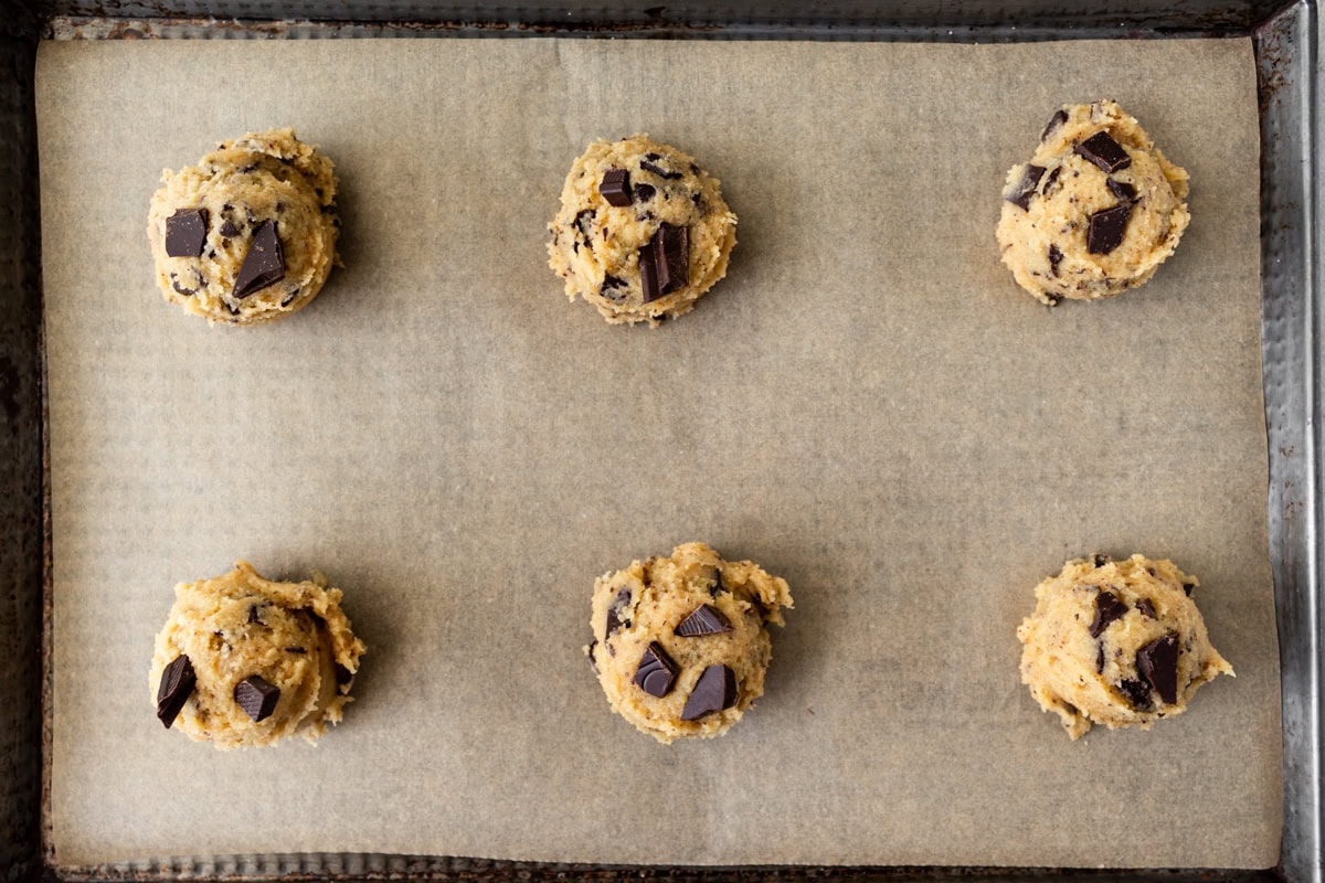 Scoops of coconut flour chocolate chip cookies dough on a parchment lined baking sheet