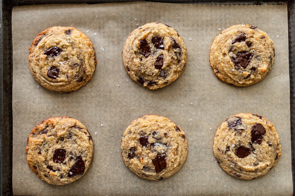 coconut flour chocolate chip cookies on a parchment lined baking sheet topped with flaky salt