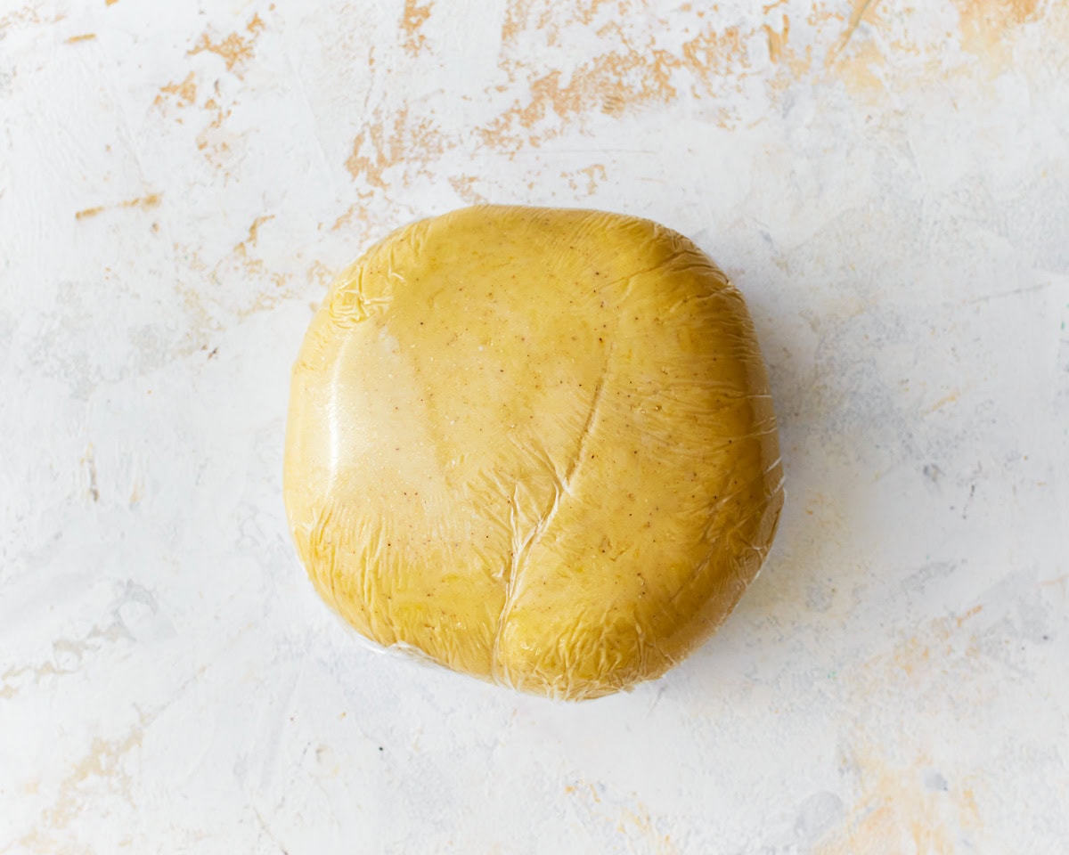 A ball of gluten-free egg noodle dough wrapped in plastic wrap