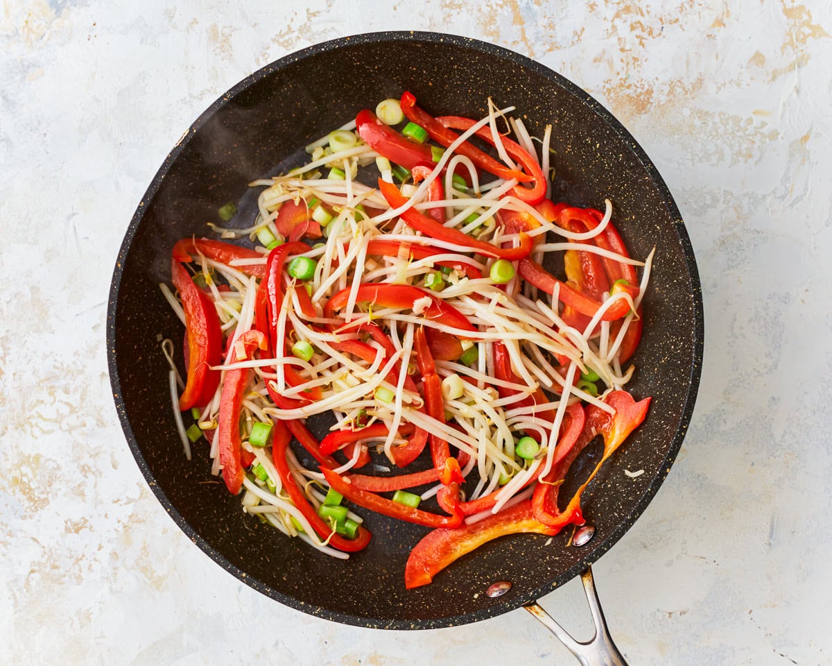 Bean sprouts, bell pepper, green onions, and garlic in a skillet for gluten-free pad thai