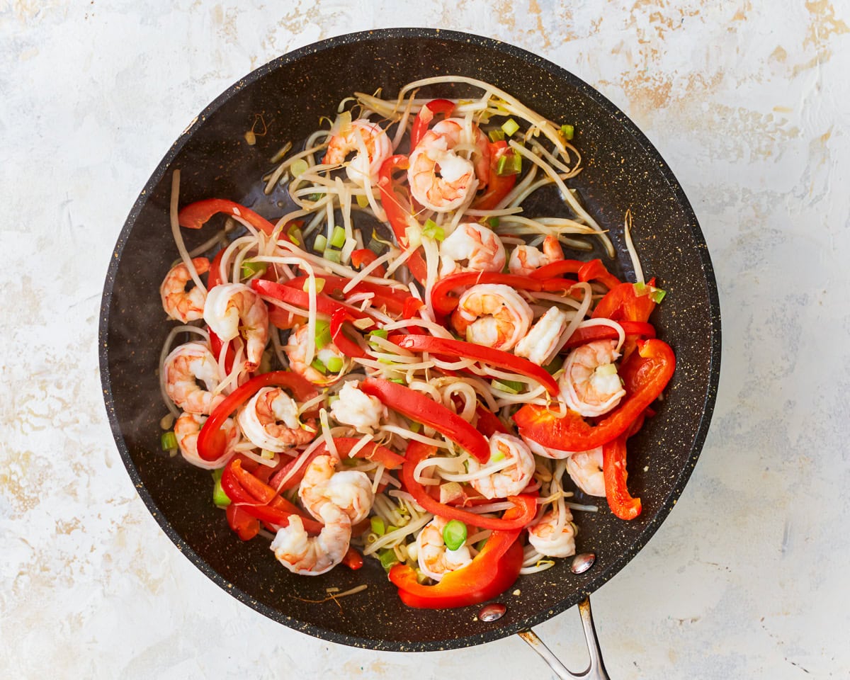 Shrimp and vegetables for gluten-free pad thai in a skillet