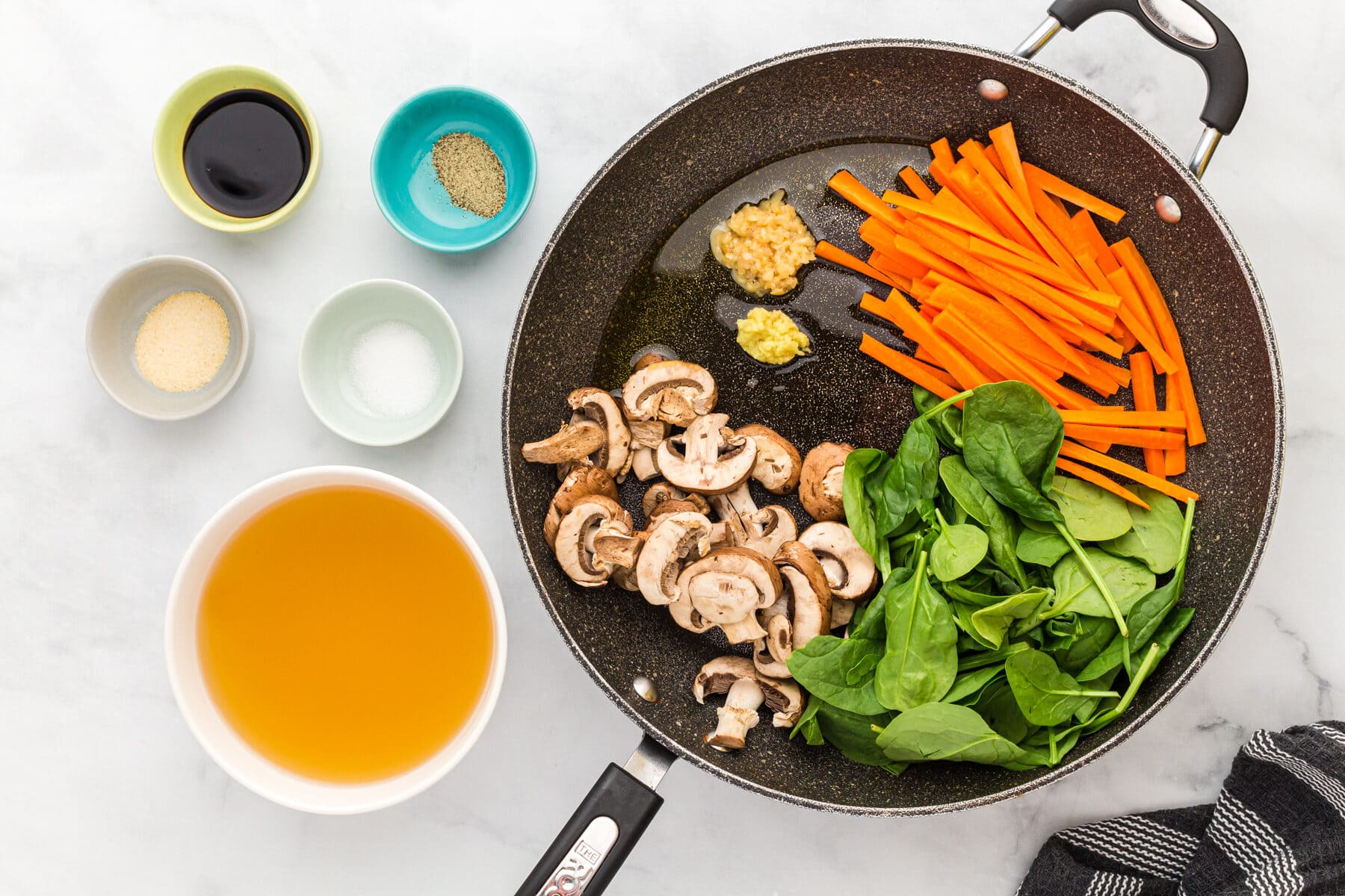 sliced carrots, baby spinach, and mushrooms in a skillet