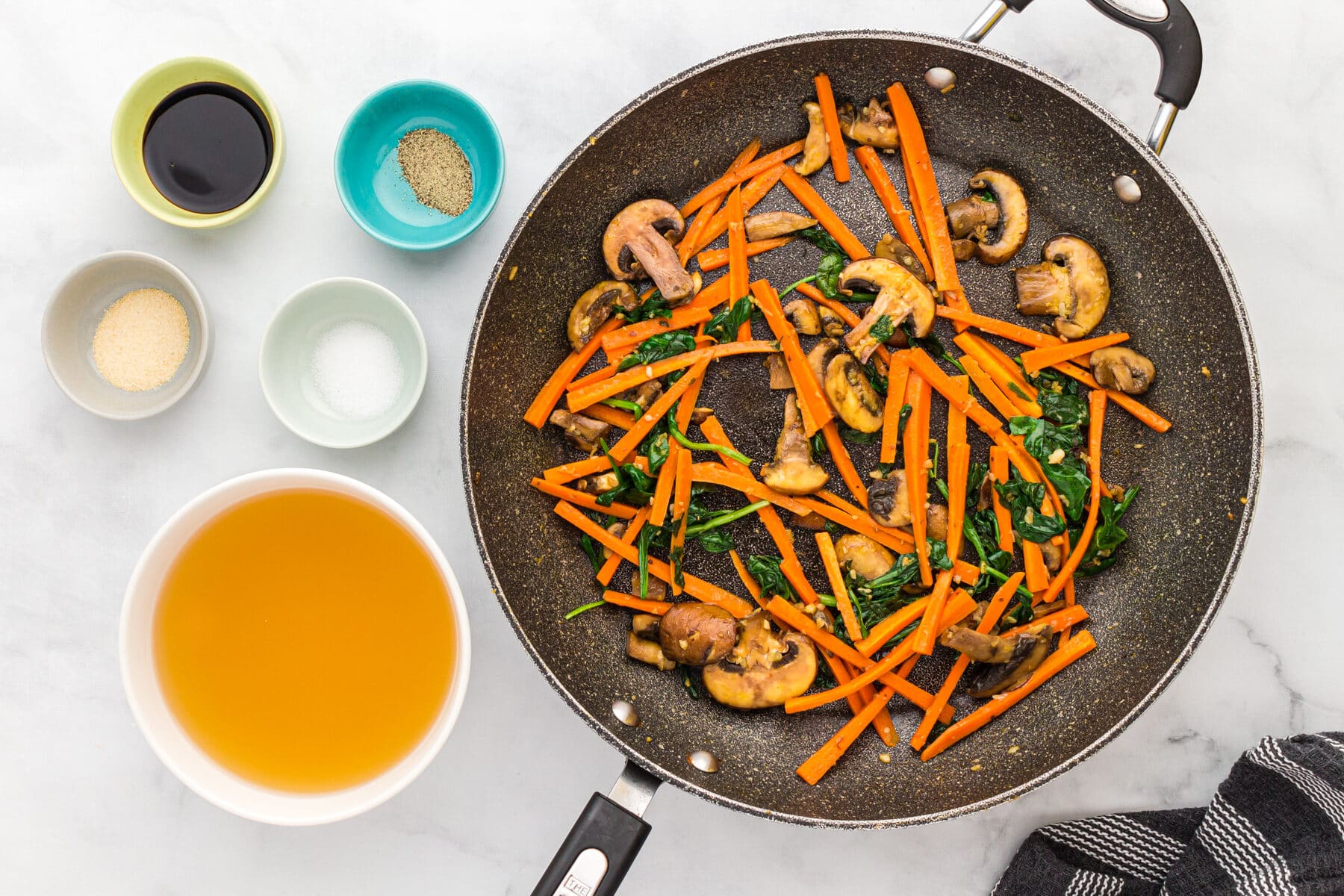 Saute carrots, mushrooms and spinach in a pan