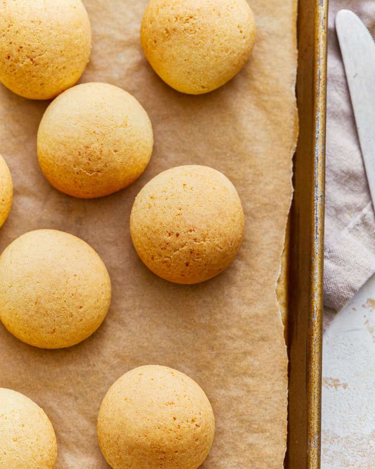 Overhead view of pandebono Colombian cheese bread on a parchment lined baking sheet