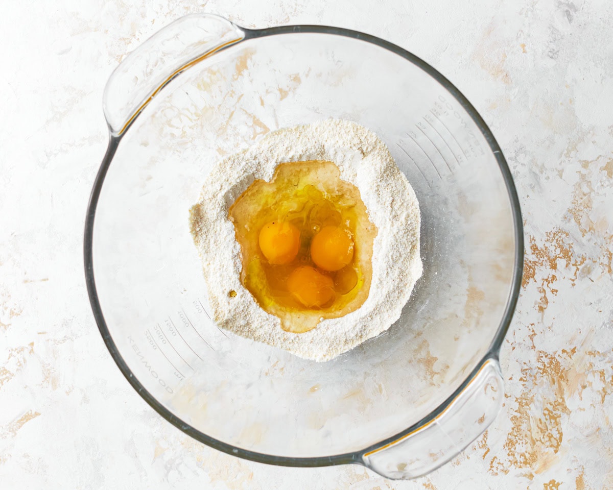 Eggs added to the dry ingredients for almond flour pasta in a bowl