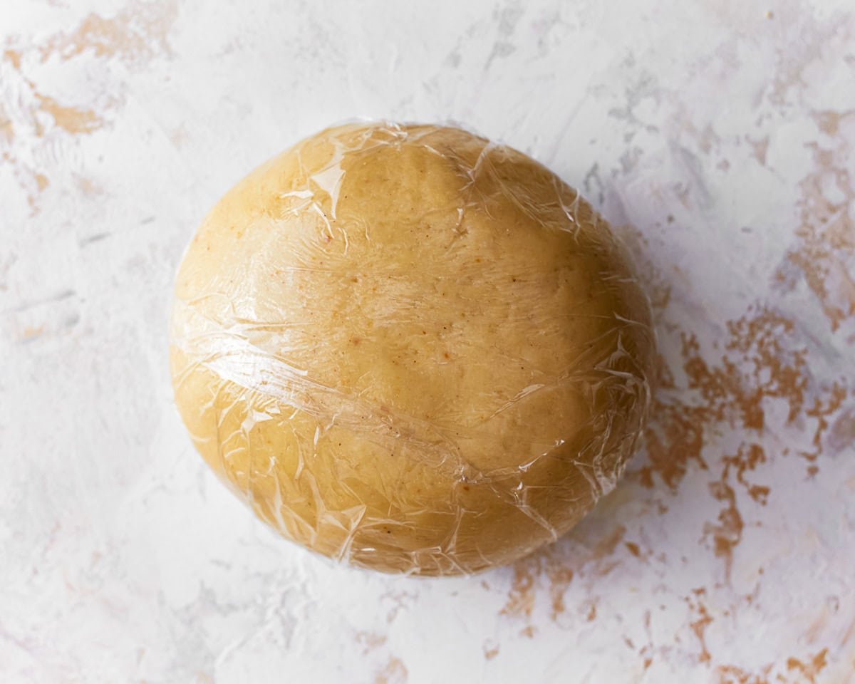 A ball of almond flour pasta dough wrapped in plastic wrap