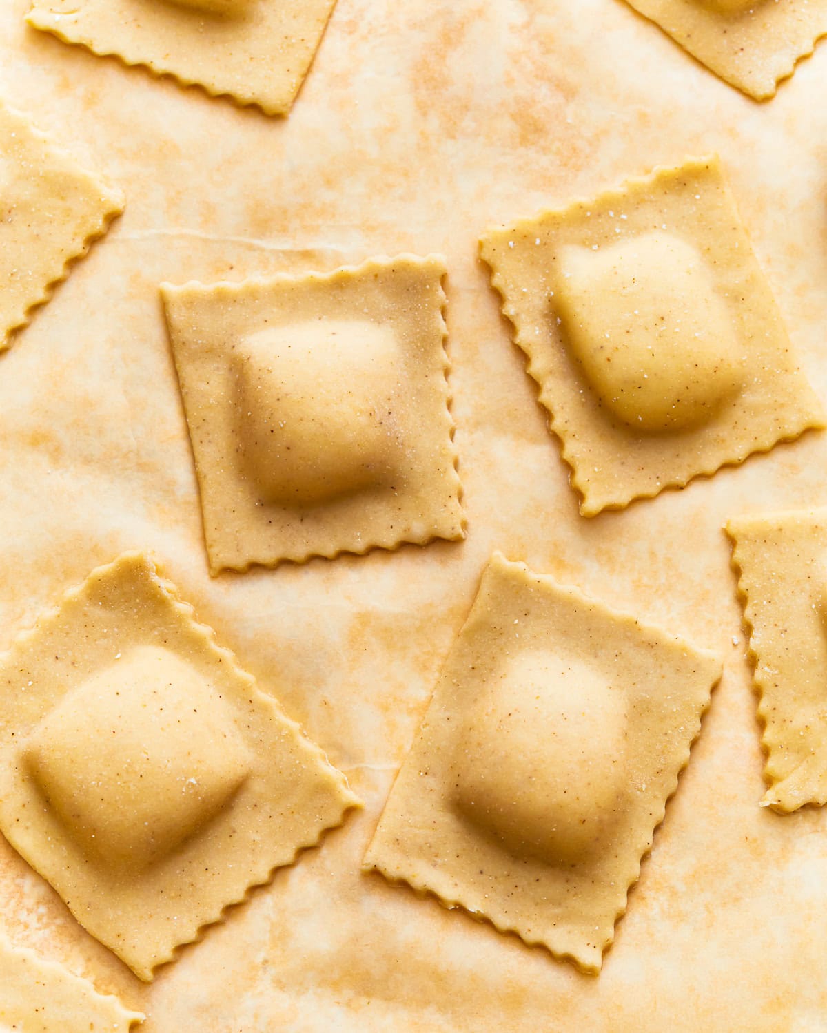 Uncooked gluten-free ravioli on parchment paper.