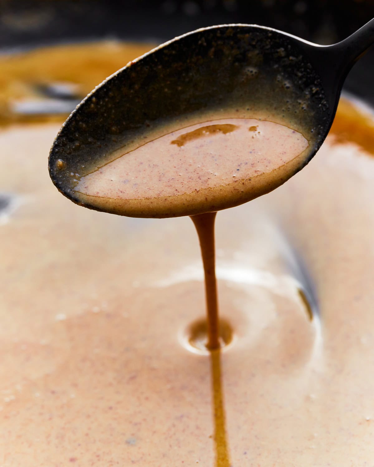 Close up of a spoon scooping gluten-free roux from a skillet.