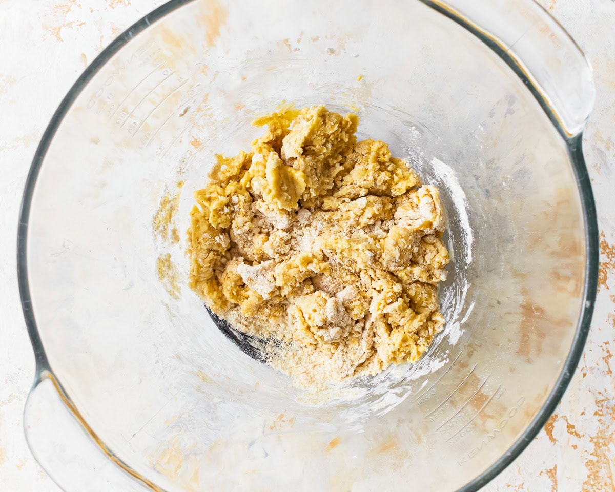 A shaggy gluten-free ravioli dough in a glass bowl.