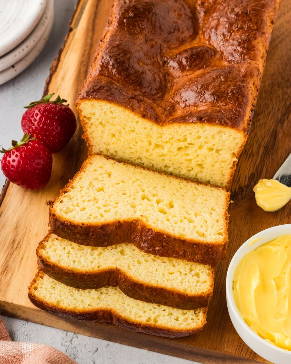 Overhead view of a sliced gluten-free brioche loaf on a wooden chopping board.