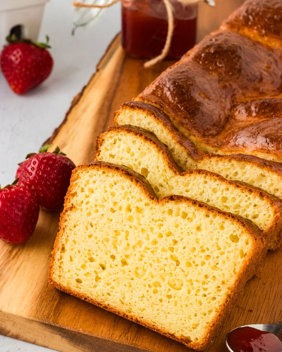 Slices of gluten-free brioche bread on a wooden chopping board.