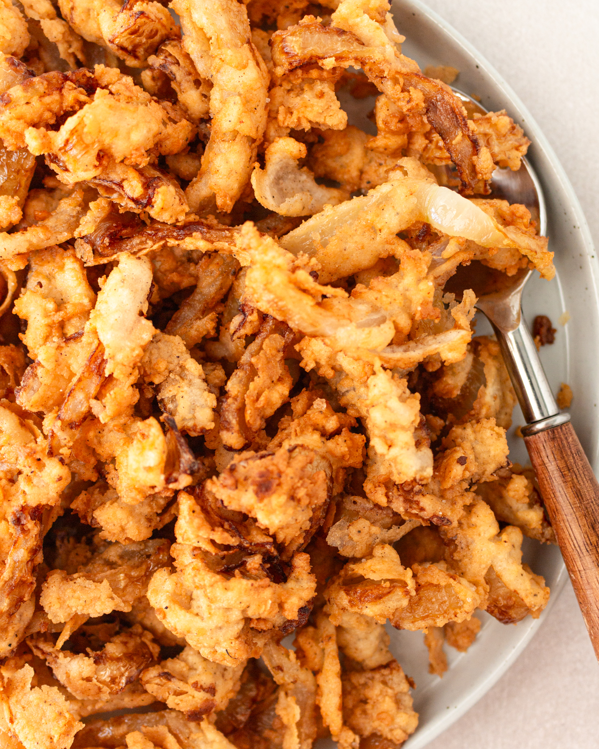 Overhead view of gluten free fried onions in a bowl with a spoon.