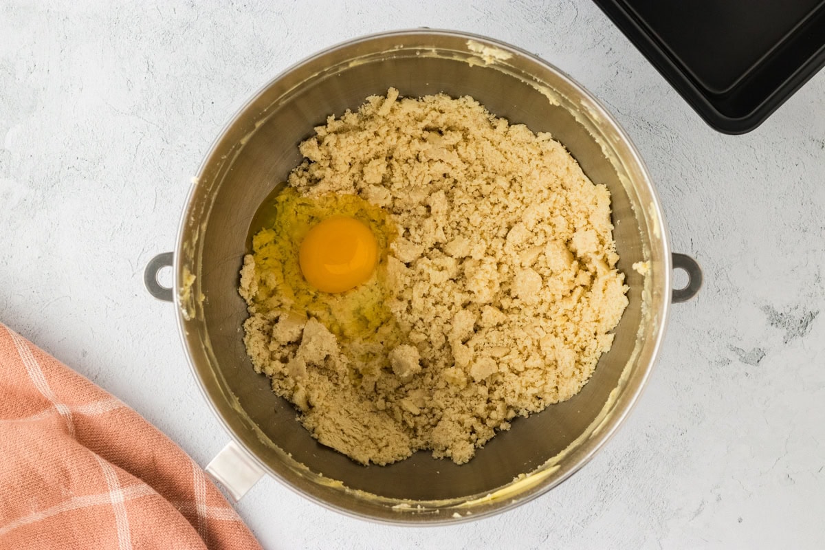 Egg added to dry ingredients for gluten-free brioche in a mixing bowl.