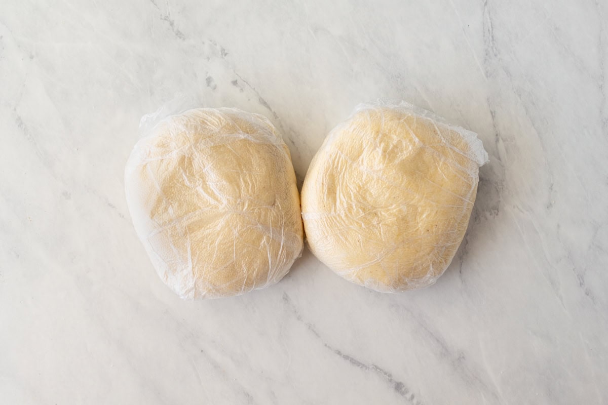 Two balls of gluten-free wonton wrapper dough wrapped in plastic wrap.