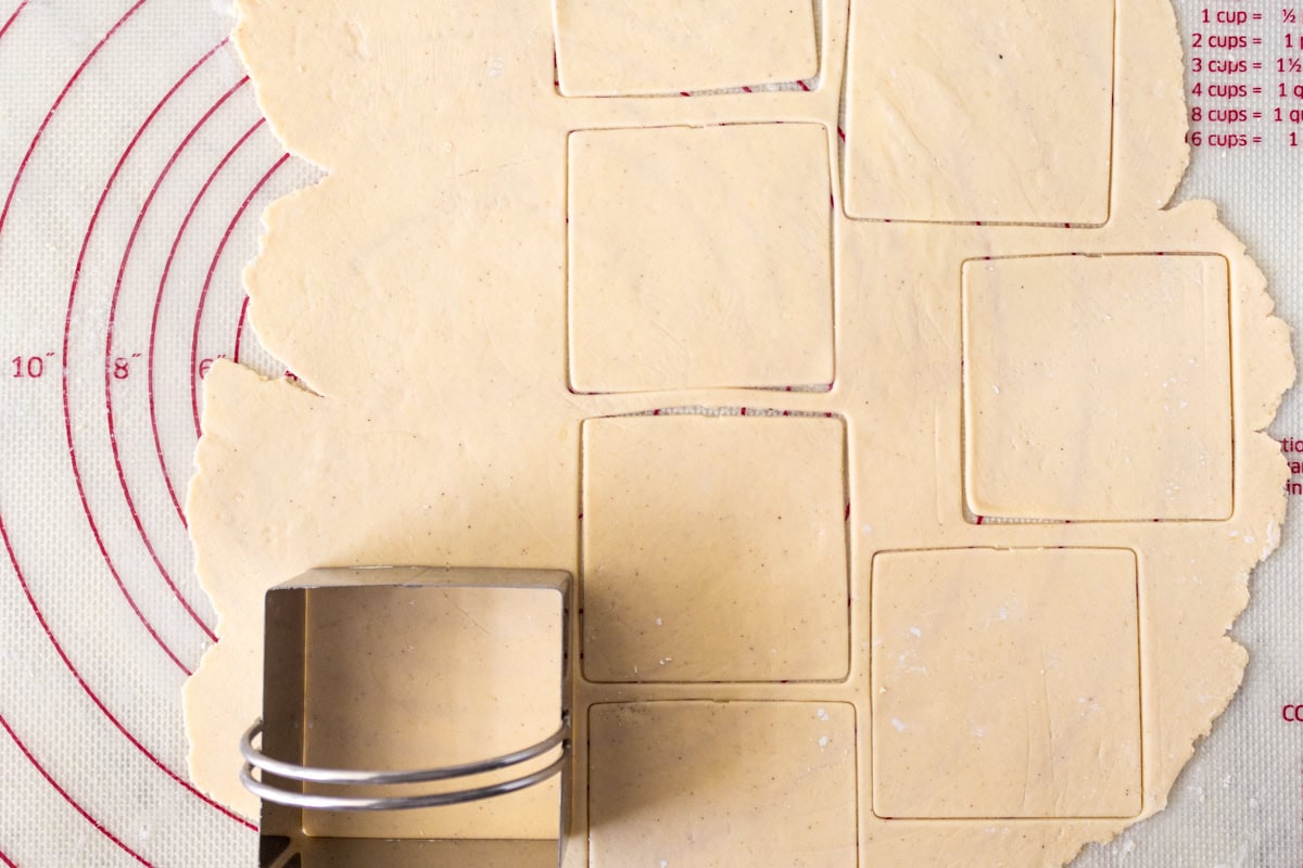 A cookie cutter cutting out squares from gluten-free wonton wrapper dough.