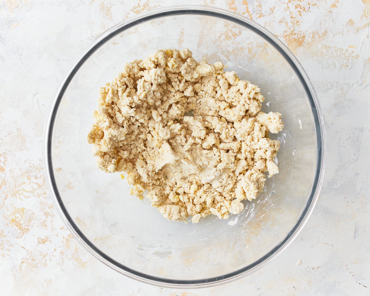 A loose dough for gluten-free puff pastry in a glass mixing bowl.