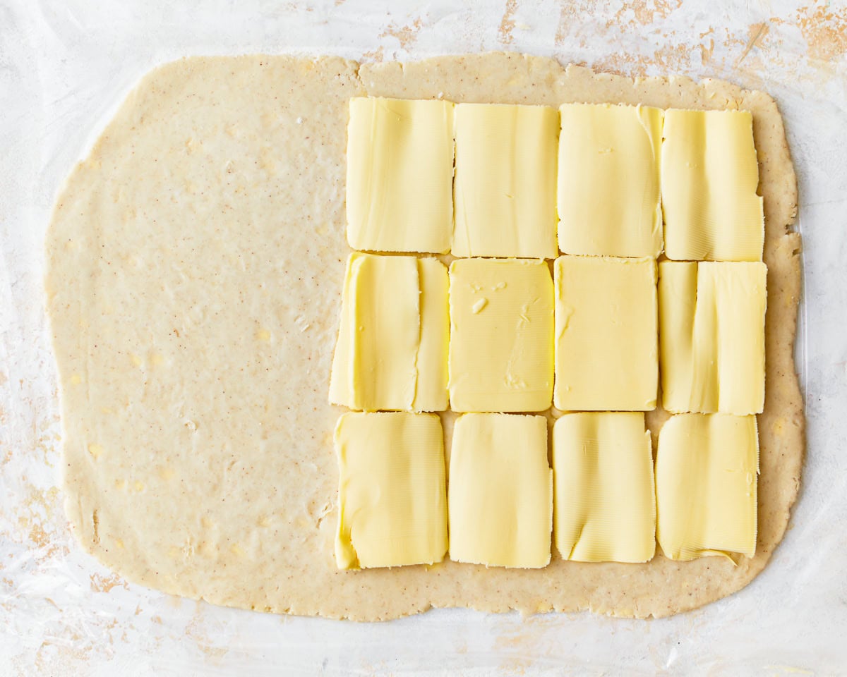 Rolled out gluten-free puff pastry dough with sliced butter on top.