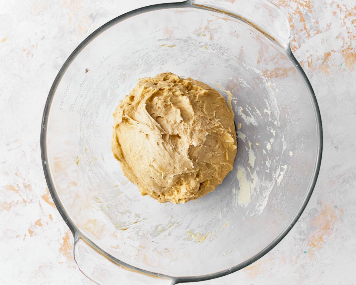 A sticky dough for gluten-free challah bread in a glass mixing bowl.