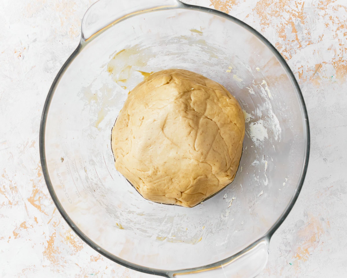 The dough for gluten-free challah bread after the first proof in a glass mixing bowl.