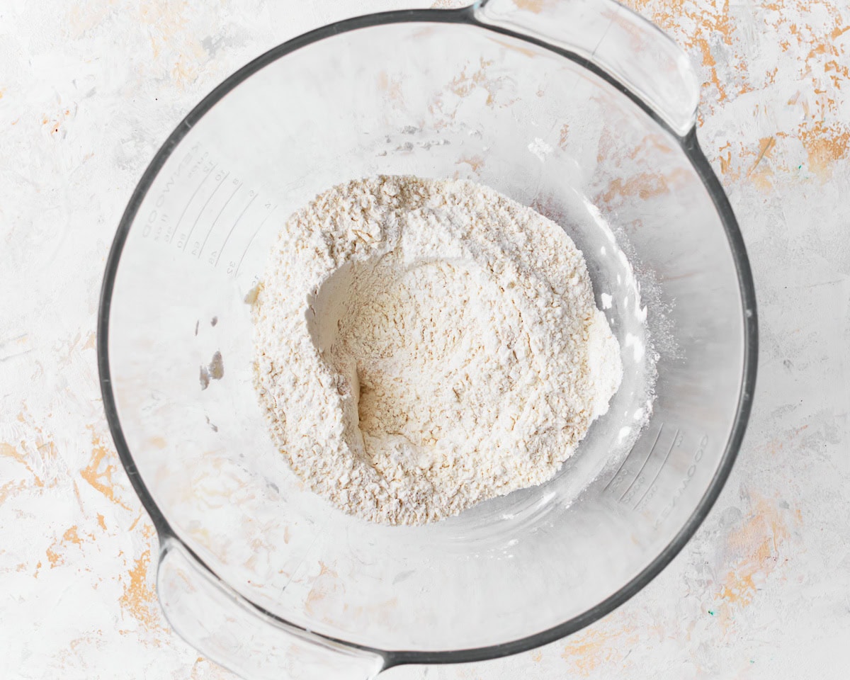 Dry ingredients for gluten-free challah bread in a glass mixing bowl.