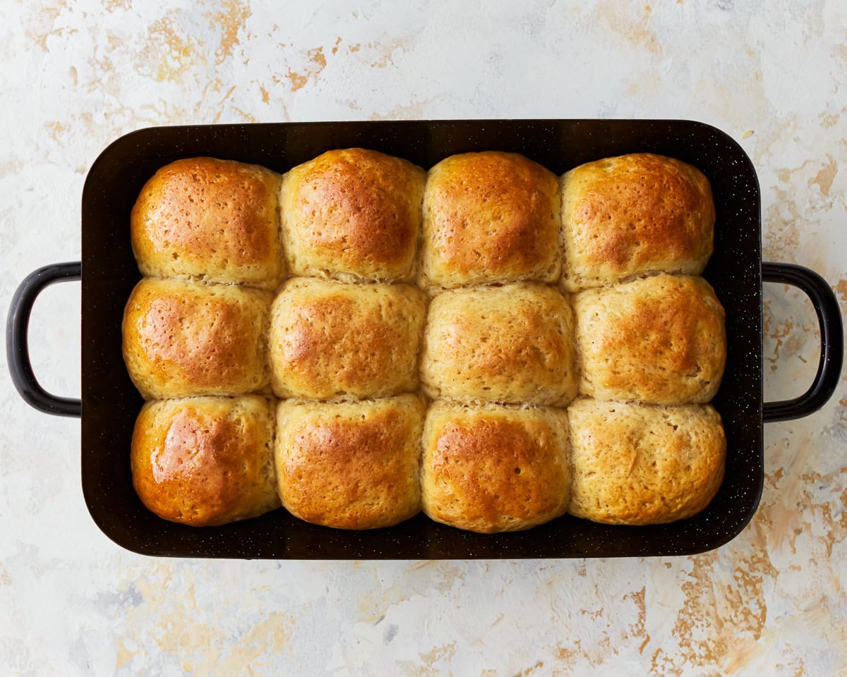 Gluten-free hawaiian rolls in a baking pan, brushed with melted butter and honey to make them shiny.