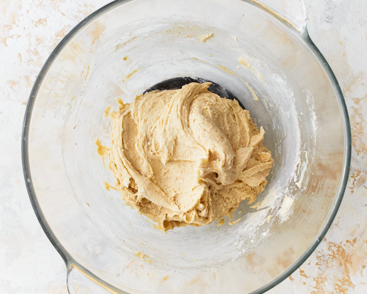 A smooth dough for gluten-free hawaiin rolls in a glass mixing bowl.