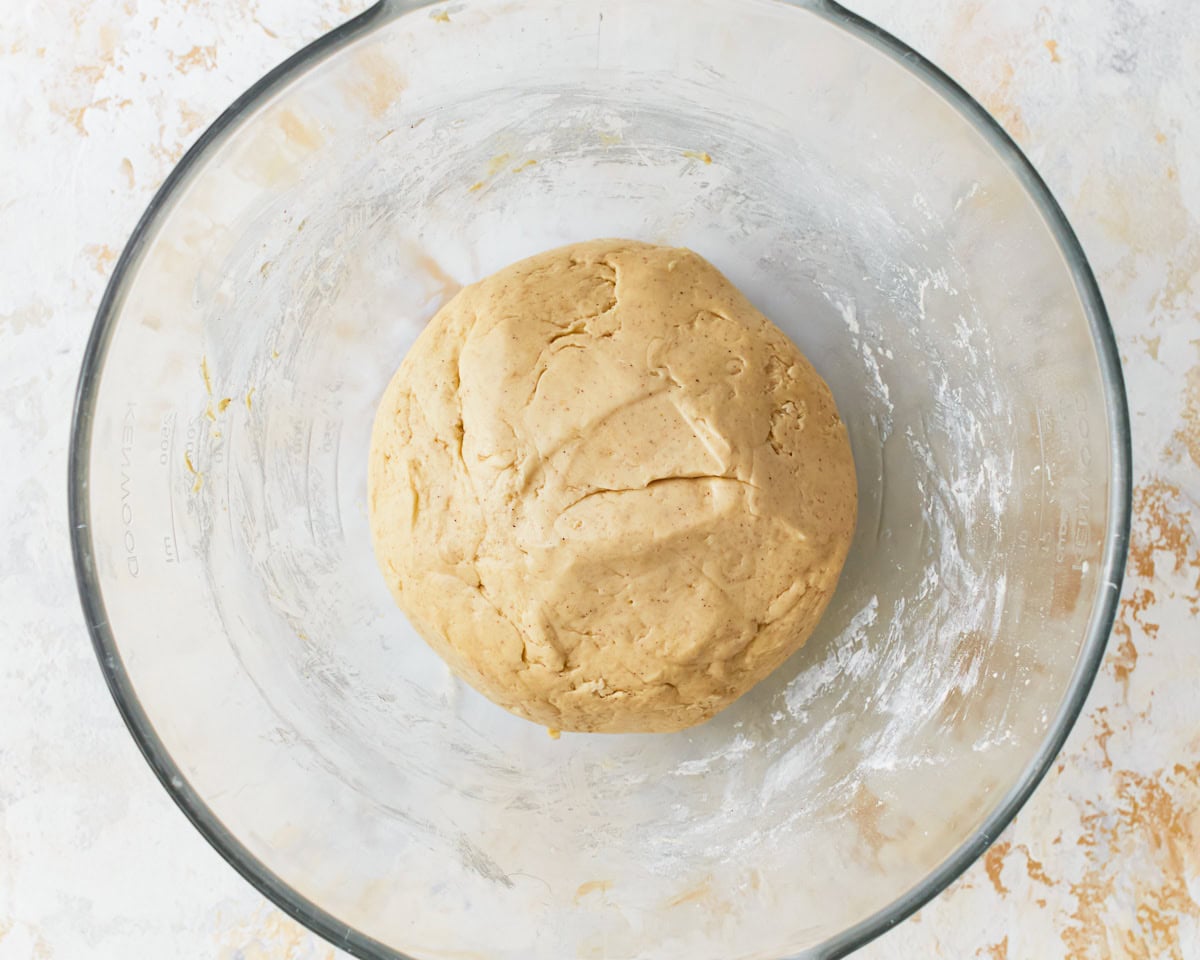 Gluten-free hawaiian roll dough after being kneaded in a glass mixing bowl.