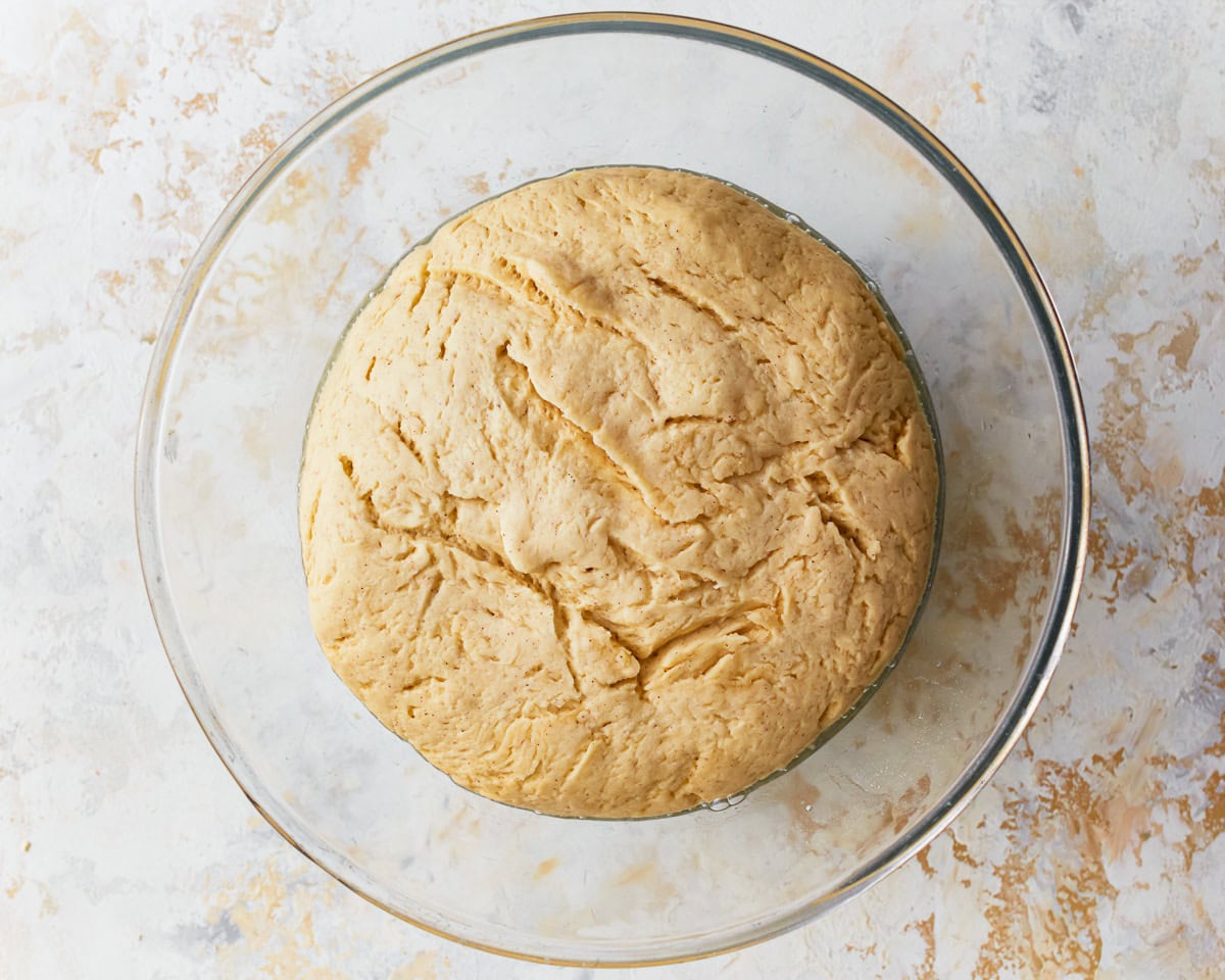 Gluten-free hawaiian roll dough in a glass mixing bowl after rising.