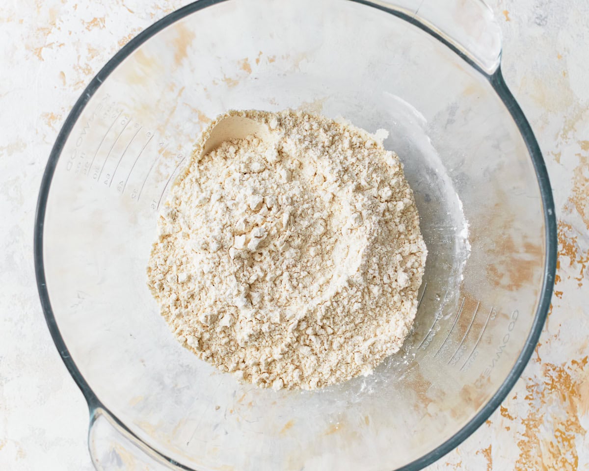 Dry ingredients for gluten-free hawaiian rolls in a glass mixing bowl.